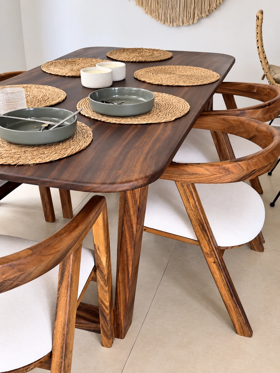 Mesa de madera de bordes redondeados con sillas de respaldo curvo y asientos claros