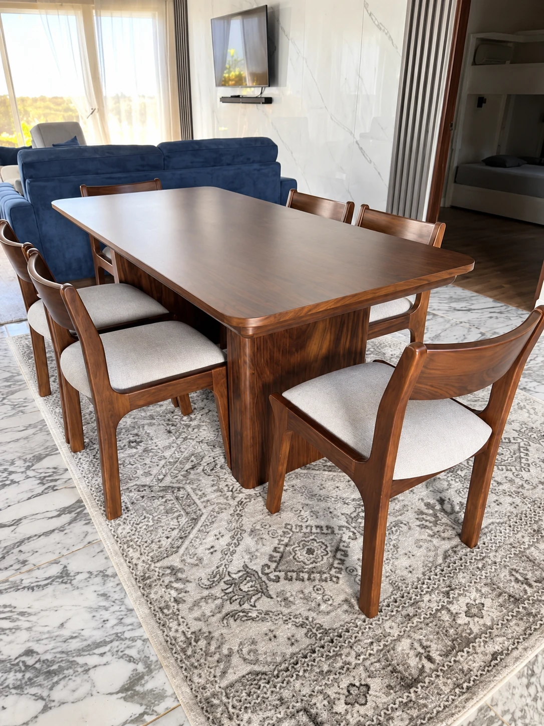 Mesa Mía rectangular de madera con base central y sillas Tania tapizadas en tono claro